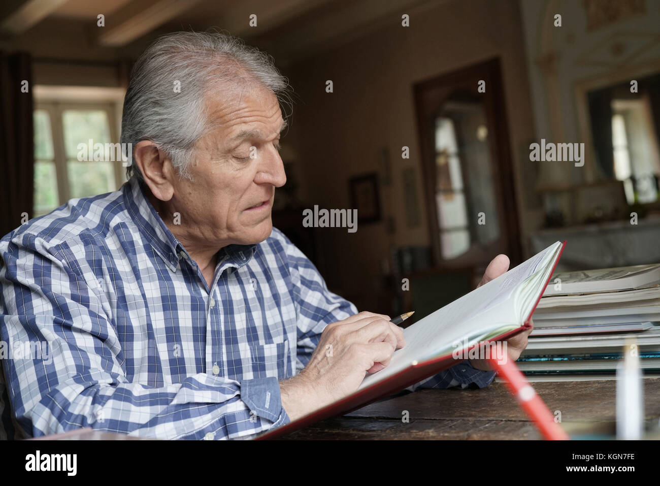 Senior man at home relaxing and writing on notebook Stock Photo