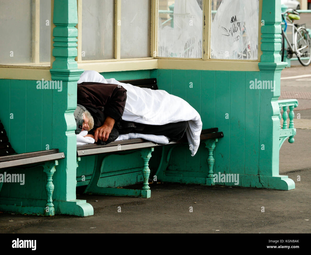 Homeless person sleeping rough in seafront shelters Brighton England