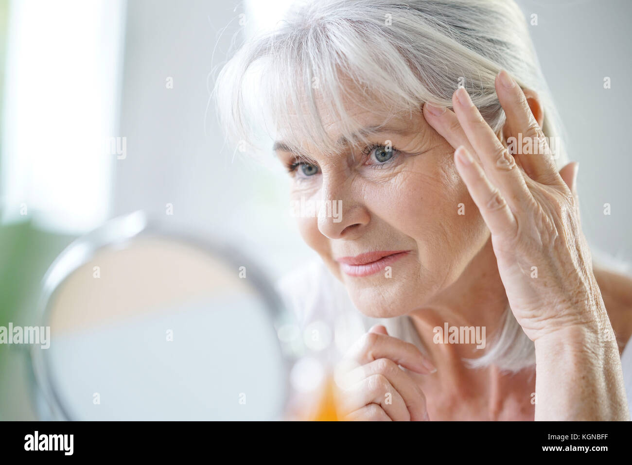 Portrait of senior woman applying anti-aging cream Stock Photo