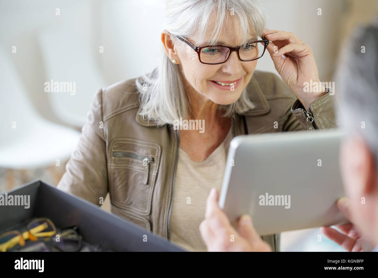 Senior woman in optical store trying eyeglasses on Stock Photo