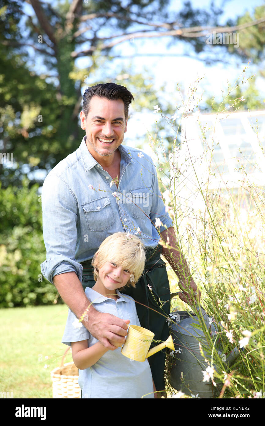 Father and son watering plants in garden Stock Photo - Alamy