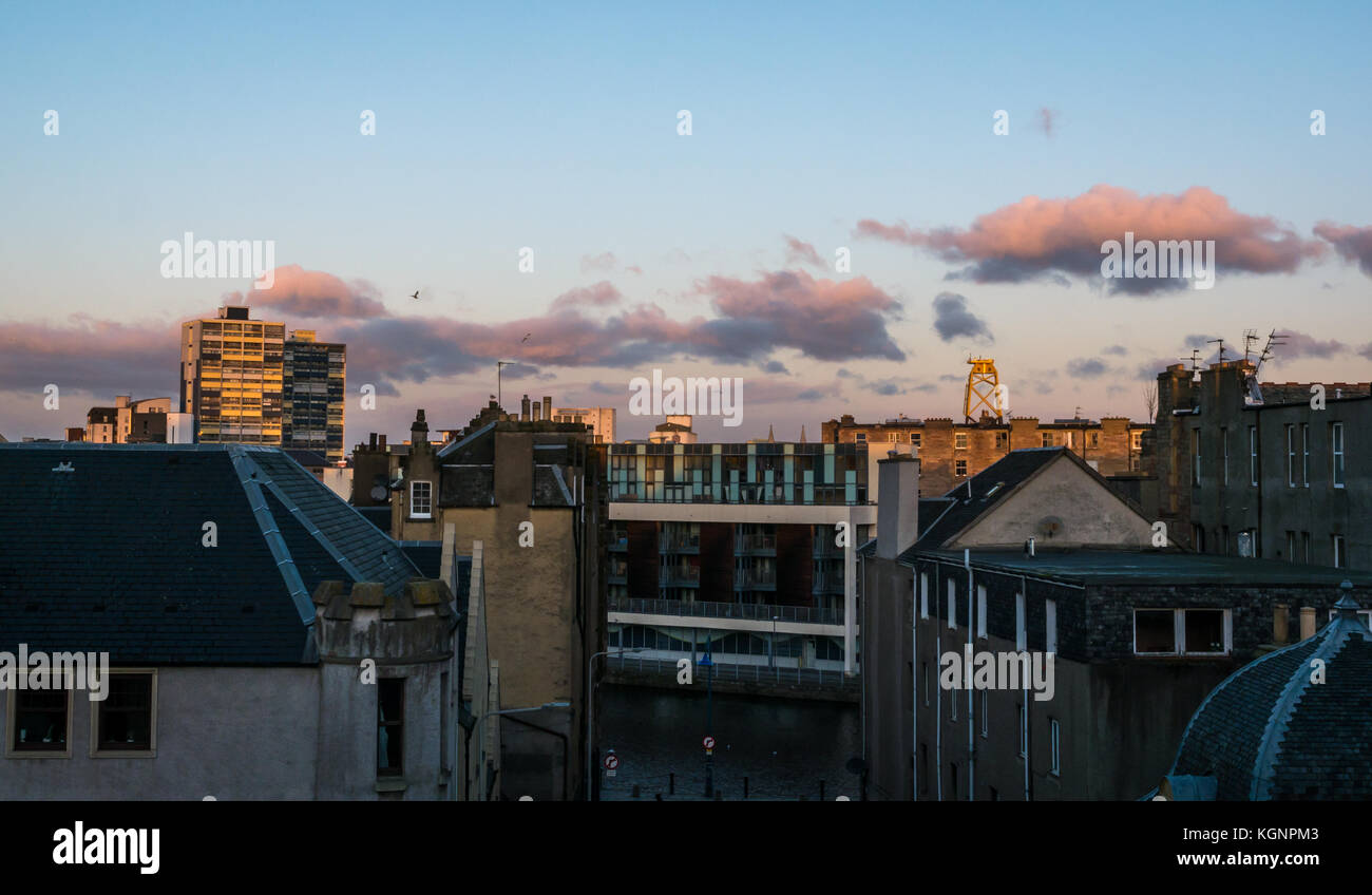 Leith, Edinburgh, Scotland, United Kingdom. Morning sunrise over Leith roofs on The Shore with pink clouds. The Couper Street council block of flats is lit by morning sunshine Stock Photo