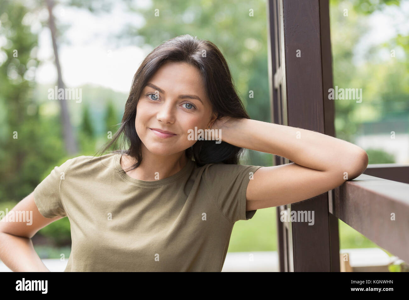 Portrait of smiling woman leaning on railing at yard Stock Photo