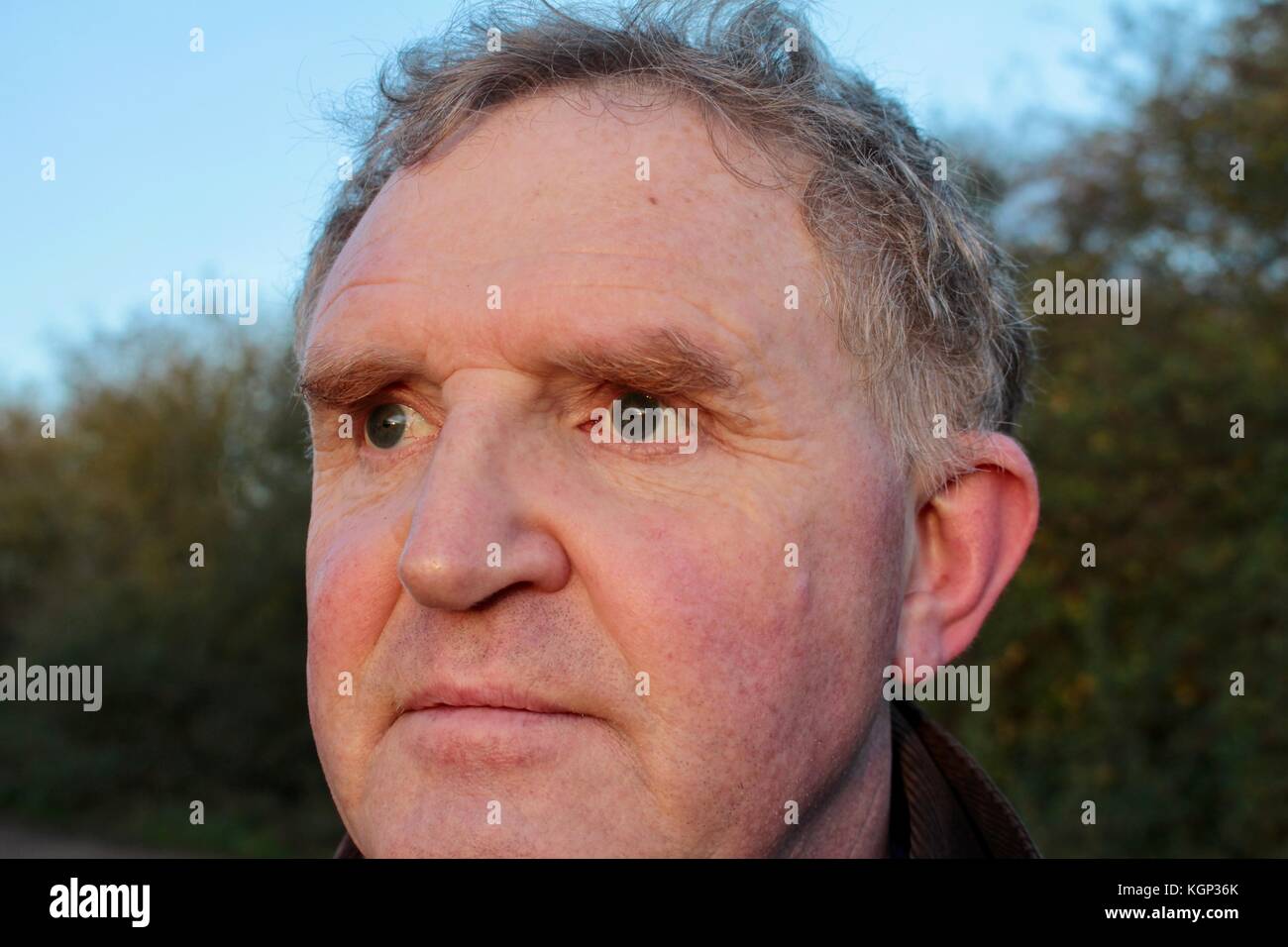 Close up face middle aged man looking into evening sun at wildfowl Stock Photo