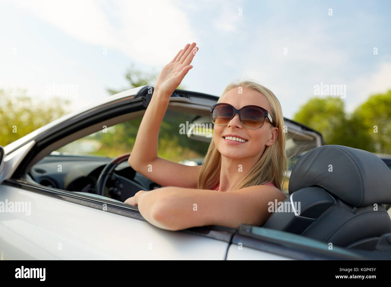 happy young woman in convertible car waving hand Stock Photo - Alamy