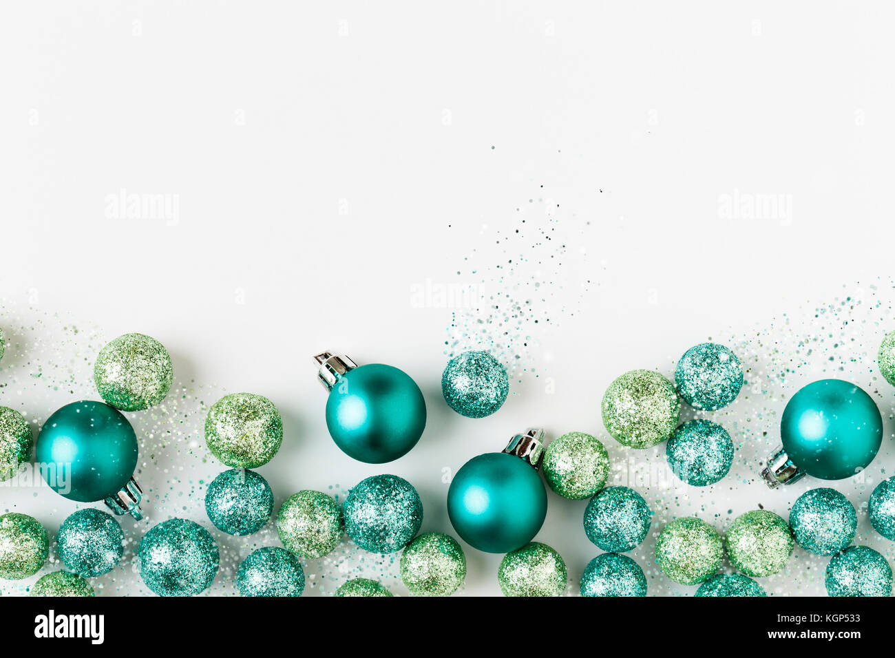 Beautiful, bright, modern, blue and green Christmas holiday ornaments decorations with sparkling glitter on white background. Horizontal border. Stock Photo