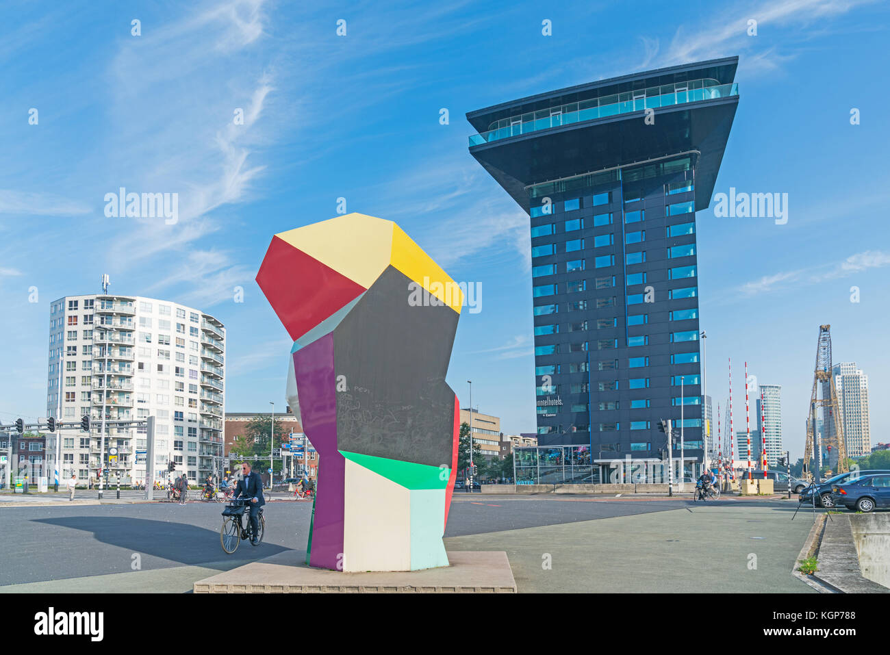 ROTTERDAM, HOLLAND -AUGUST 22, 2017; Man cycles past multi-colored cubic Marathon Image sculpture in Erasmuburg district with one of city's stunning m Stock Photo