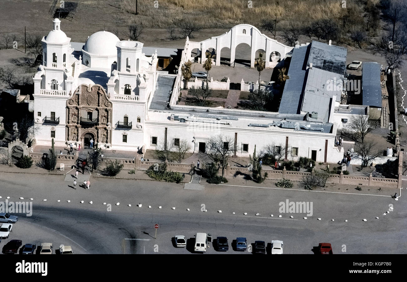 An aerial view shows the historic Spanish Mission San Xavier del Bac on the Tohono O'odham San Xavier Indian Reservation on the outskirts of Tucson, Arizona, USA. Known as the 'White Dove of the Desert' because of its bright lime-washed exterior, the Catholic mission was constructed from 1783-97 by local natives under direction of Franciscan missionaries. Seen is its ornate entrance flanked by two towers (one unfinished) and adjoining buildings that once housed schoolrooms around the open courtyard. The mission is one of the finest examples of Spanish Colonial architecture in the United States Stock Photo