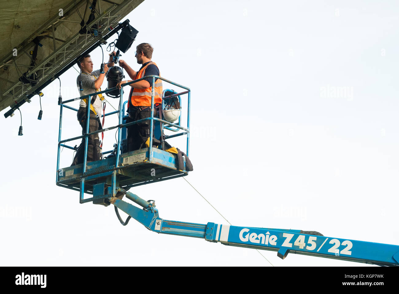 Working at  height:  Two technicians standing in a cherry picker cradle installing the lighting rig at a summer music festival UK Stock Photo