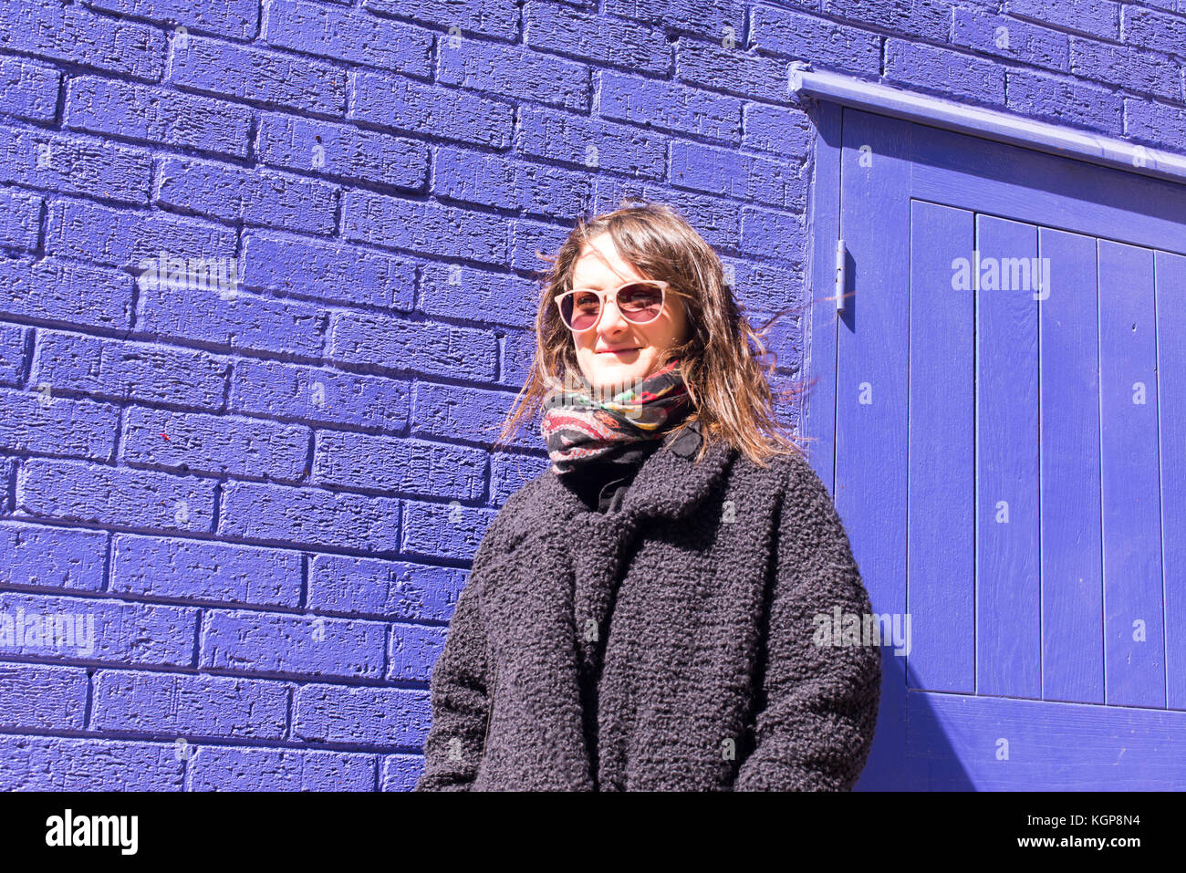 A woman wearing sunglasses standing in front of a wall photo