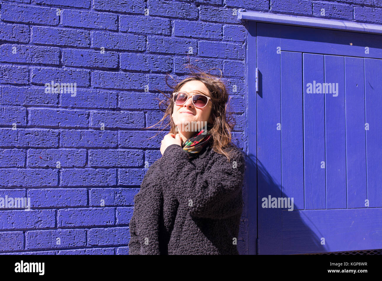 A woman wearing sunglasses standing in front of a wall photo