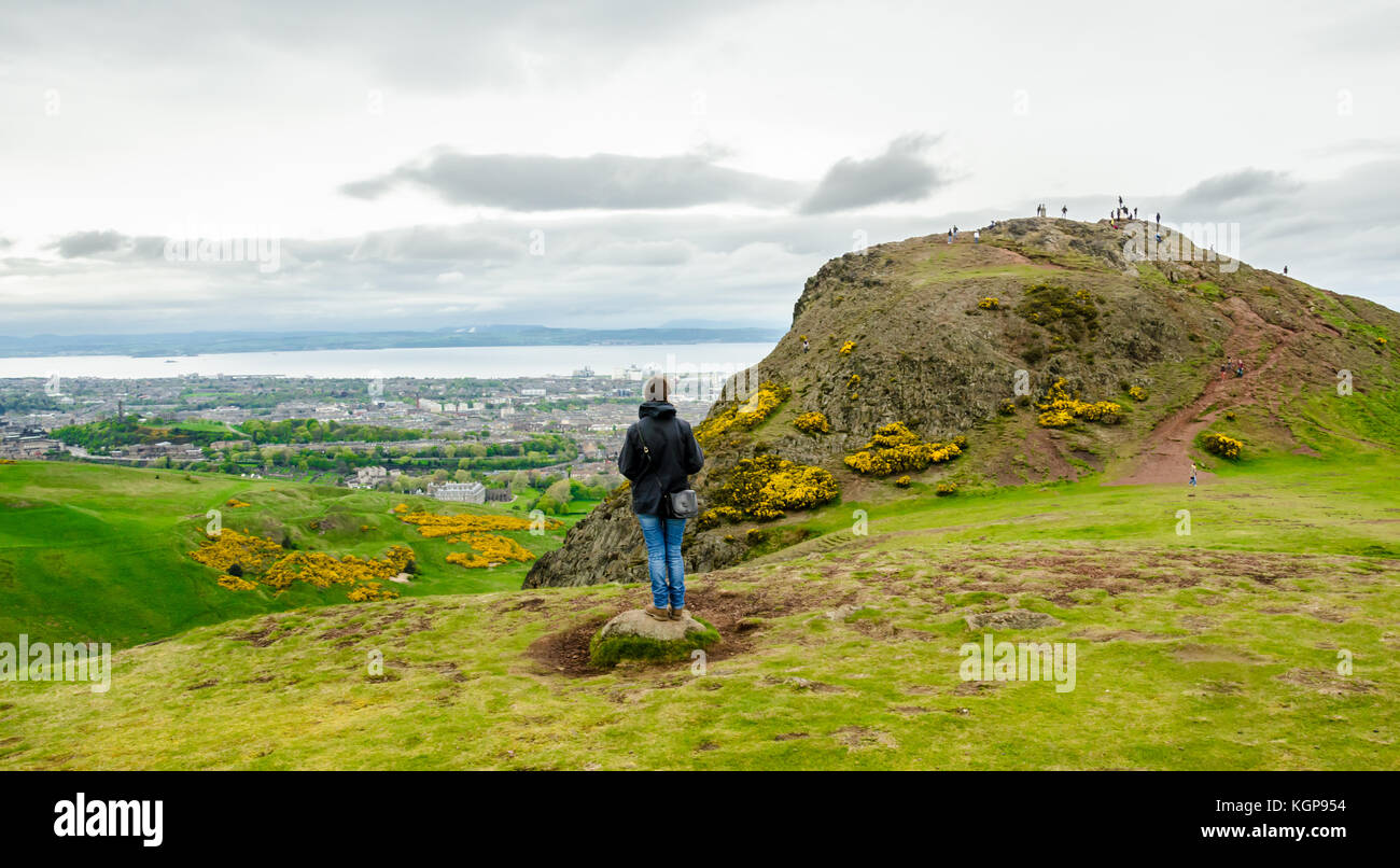 Young female model admiring Edinburgh landscape from the top of the Arthur's seat. Scotland, UK. Stock Photo