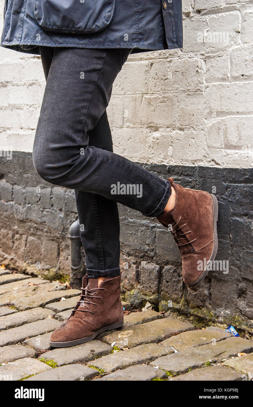 Model legs wearing tight black skinny trousers and brown ankle boots. Black and white brick wall as a background. Stock Photo