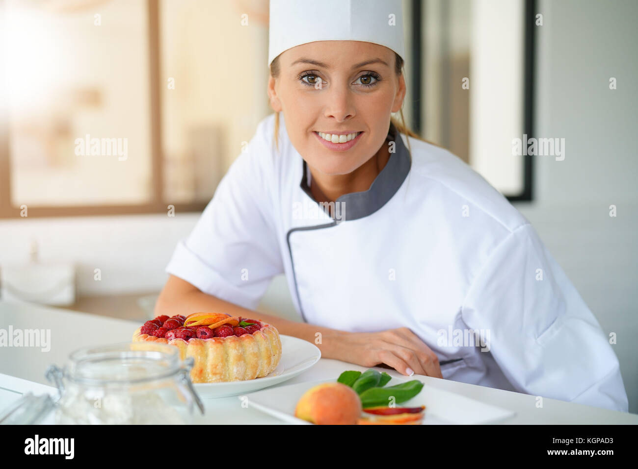 Portrait of pastry chef standing by raspberry cake Stock Photo