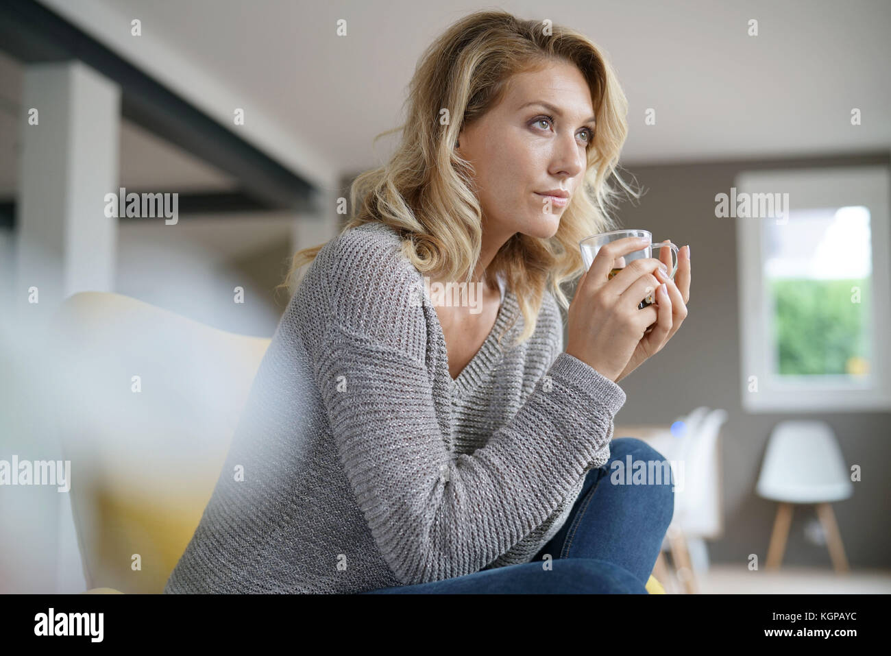 Beautiful woman relaxing in armchair with hot drink Stock Photo - Alamy