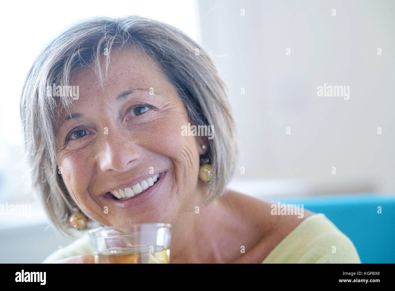 Senior woman relaxing in armchair drinking hot tea Stock Photo