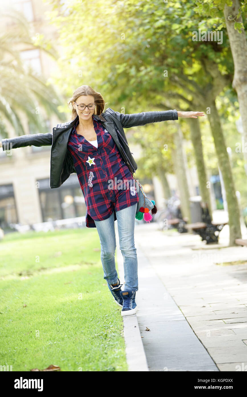Trendy girl walking on parapet, balancing Stock Photo Alamy