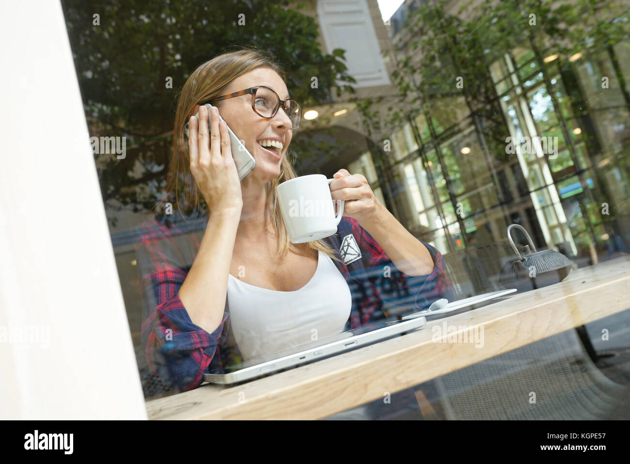 Trendy city girl in coffee shop connected with smartphone Stock Photo