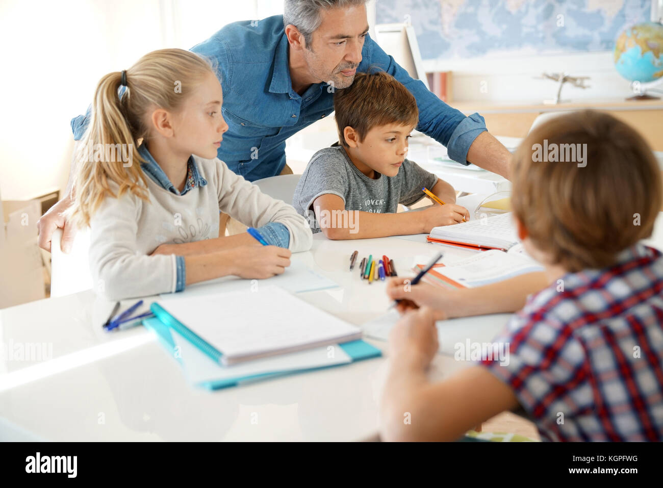 Teacher with kids in class giving writing lesson Stock Photo