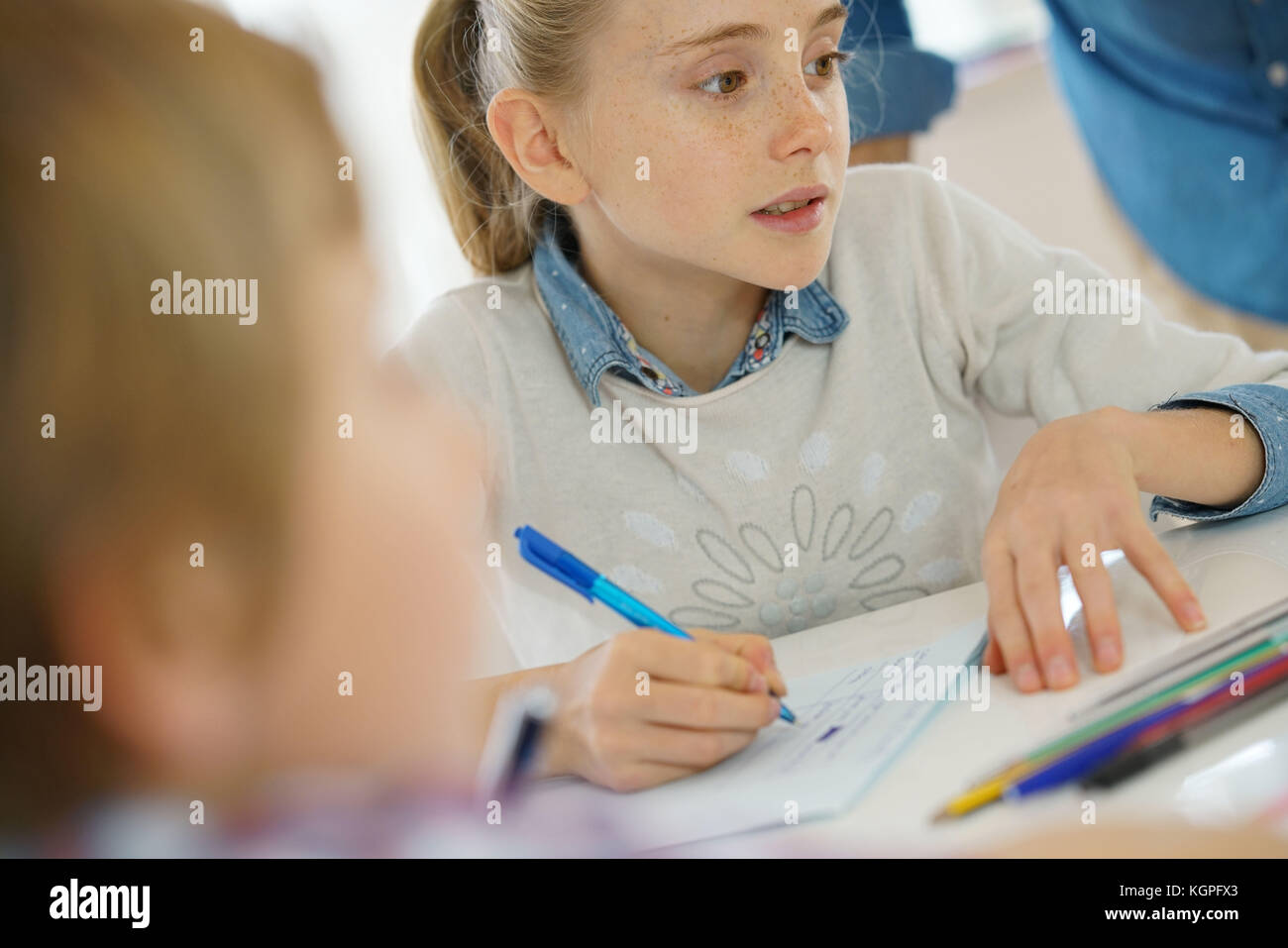 Portrait of school girl taking notes in class Stock Photo