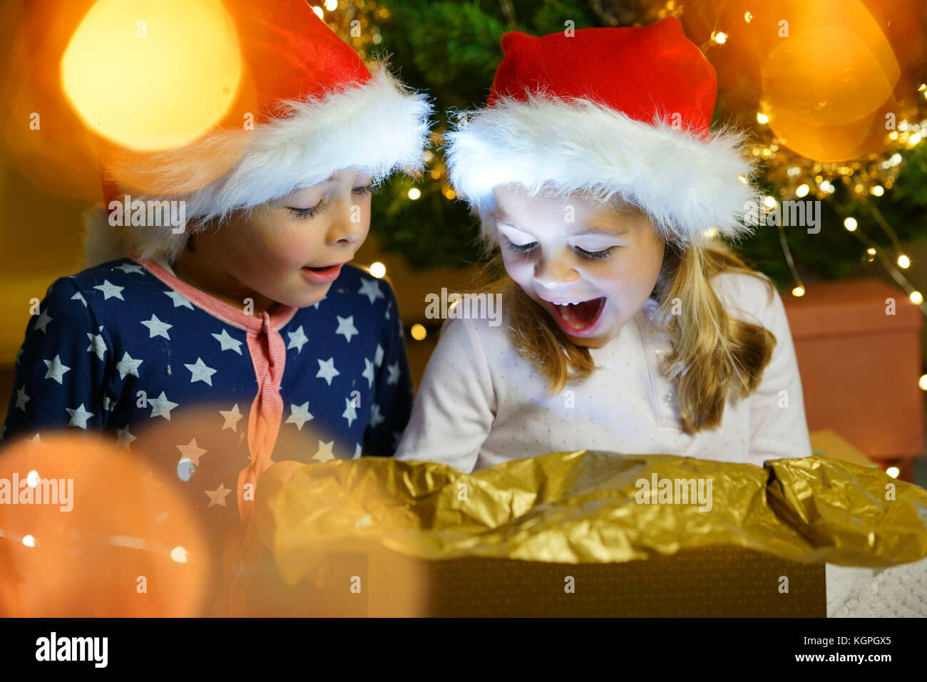 Kids being surprised while opening Christmas gift Stock Photo