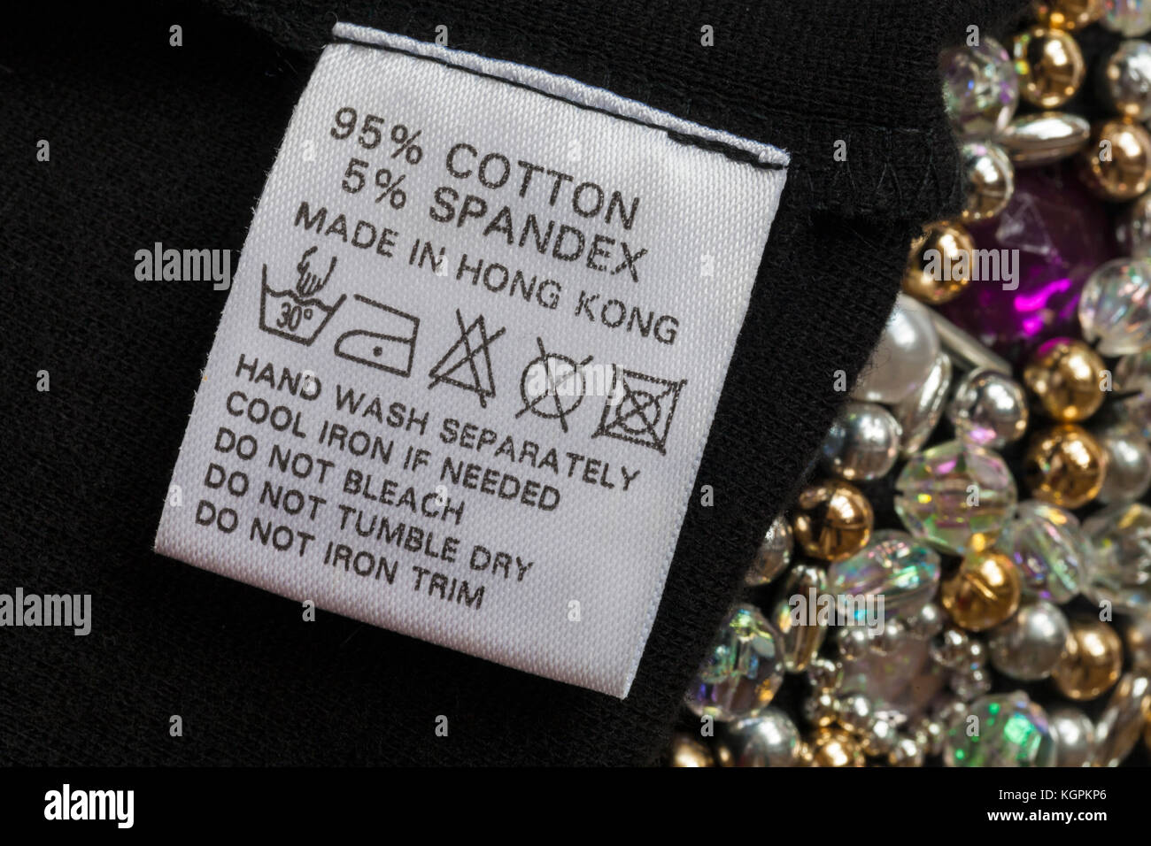 95% cotton 5% spandex label  in woman's little black dress with beads made in Hong Kong with wash care symbols and instructions Stock Photo