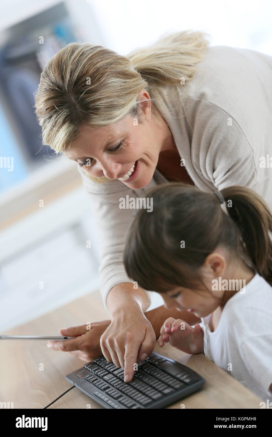Teacher with little girl in class using computer and tablet Stock Photo ...