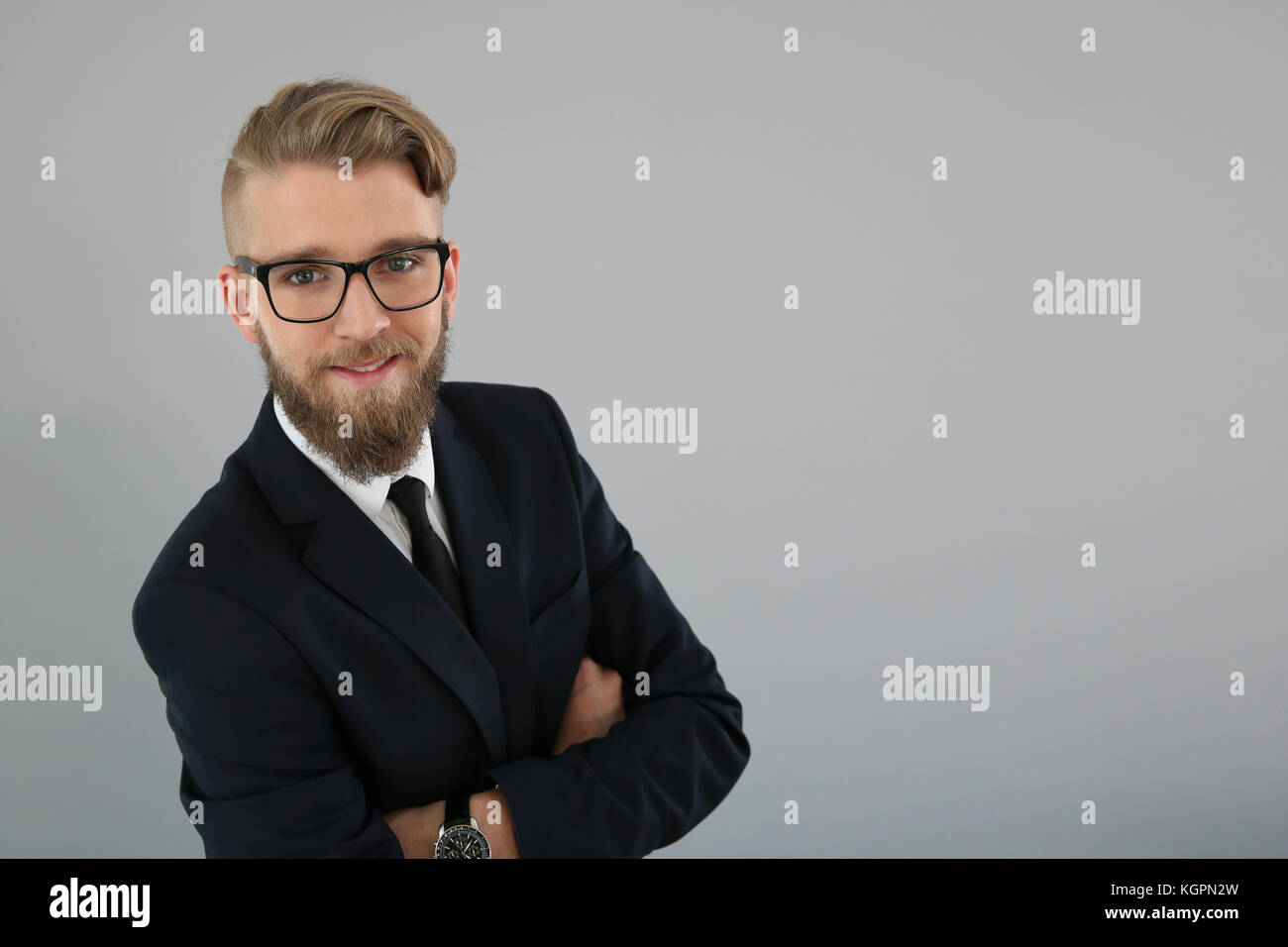 Smiling young businessman on grey background Stock Photo - Alamy