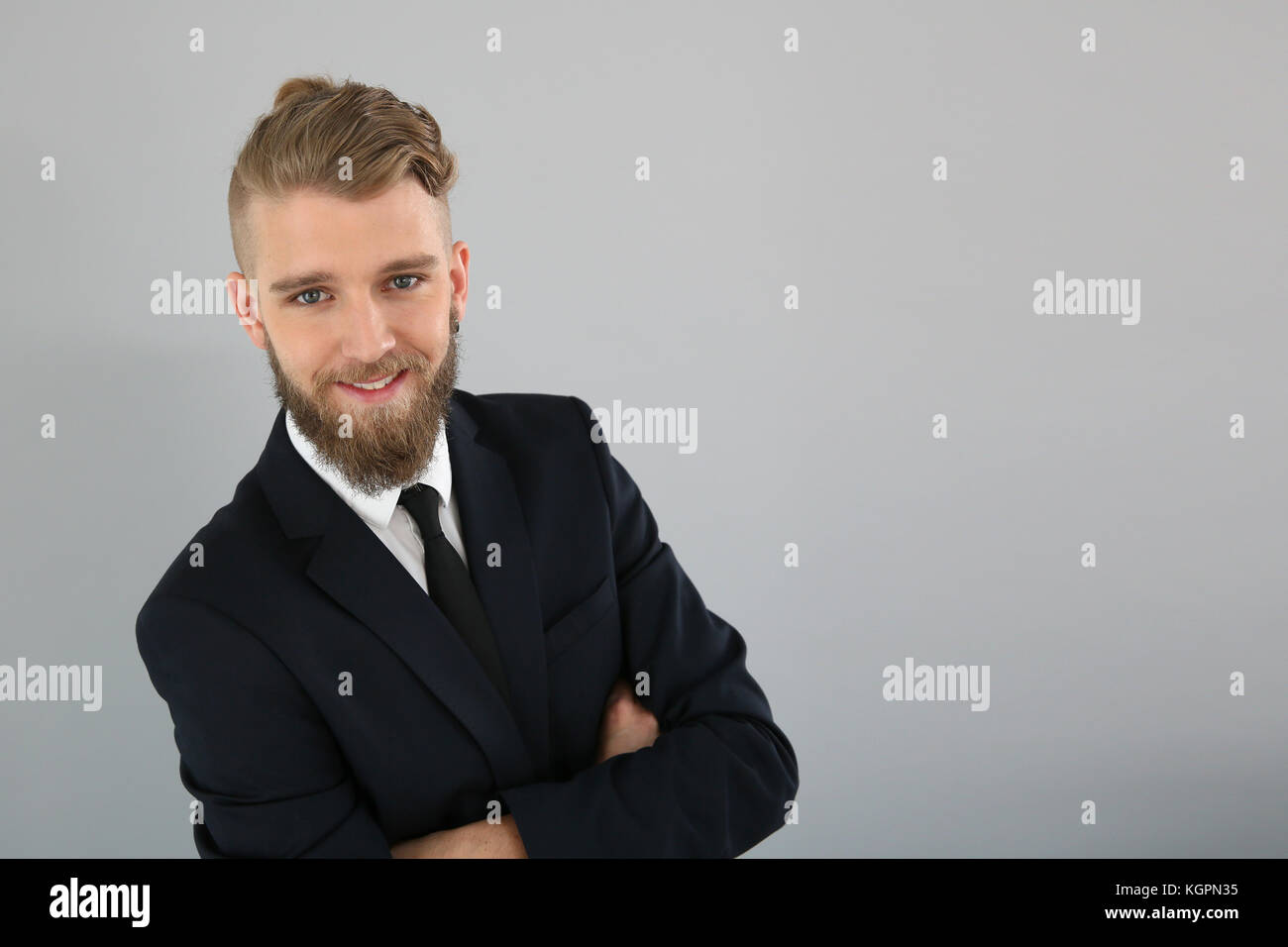 Smiling young businessman on grey background Stock Photo - Alamy
