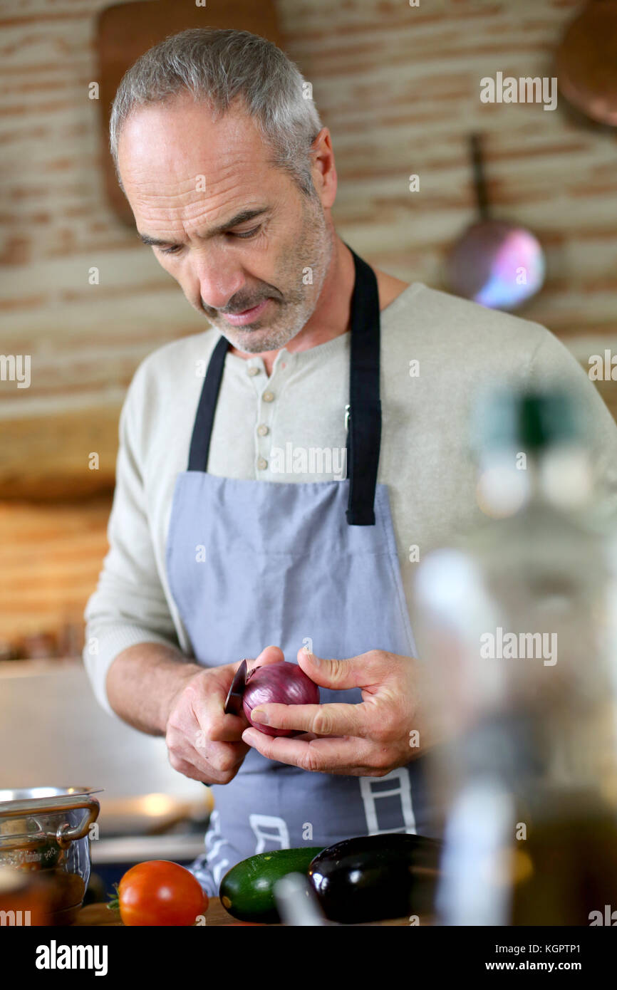 Mature handsome man cooking in home kitchen Stock Photo