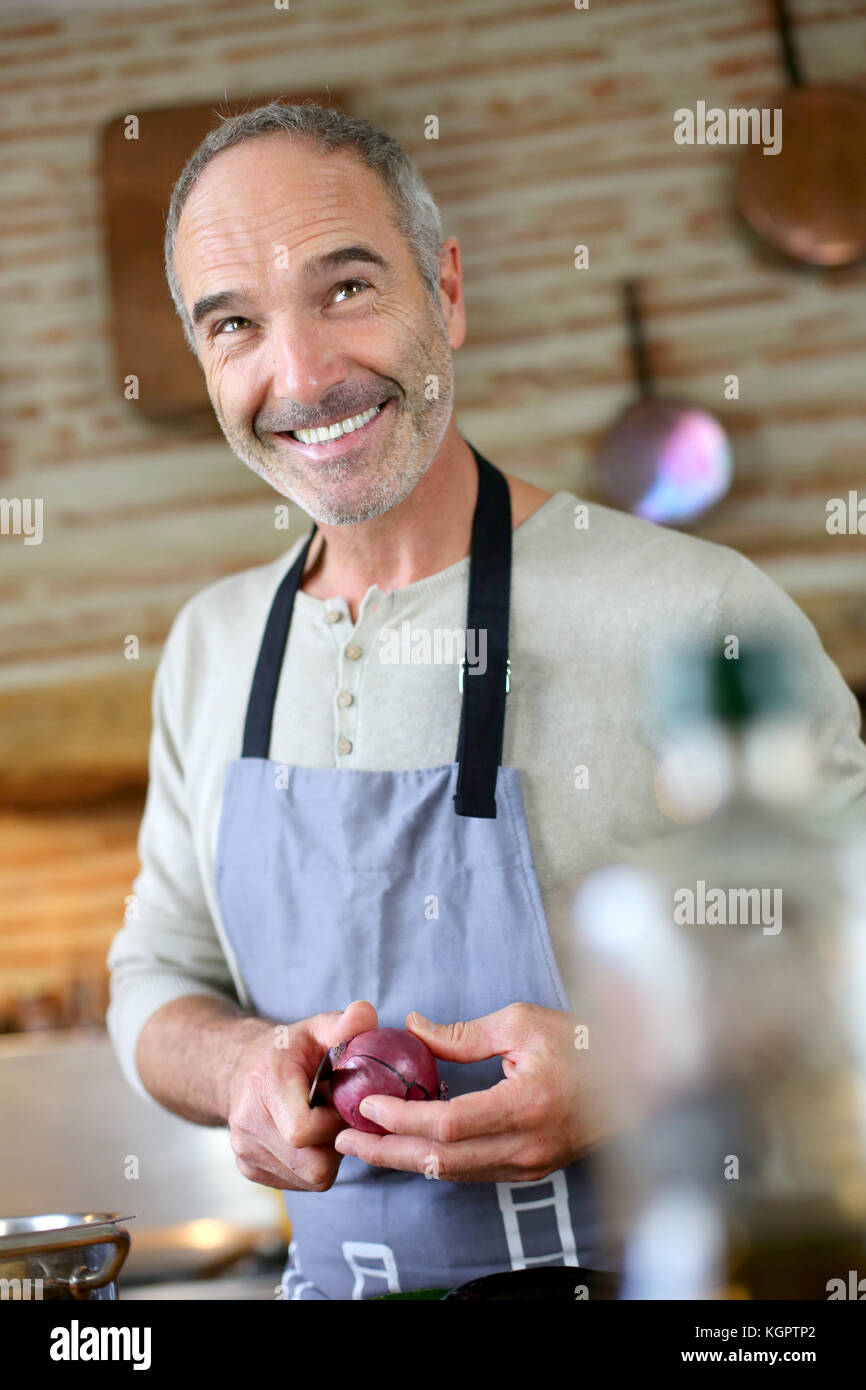 Mature handsome man cooking in home kitchen Stock Photo