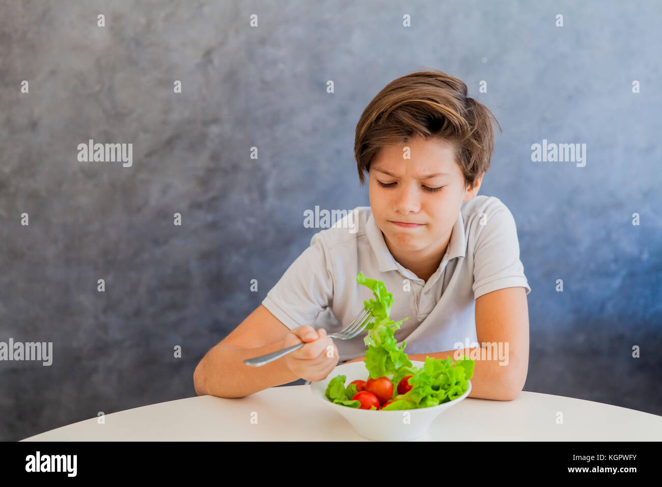 Cute teen boy dont like eating salad Stock Photo - Alamy