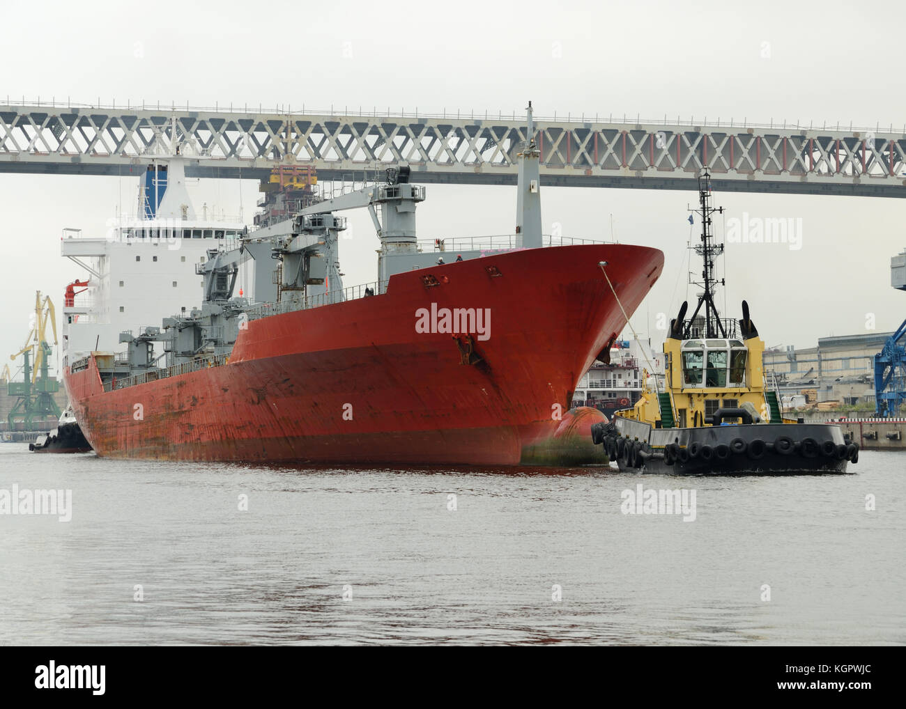 Tugboat pulling a large tanker from the port after it is downloaded. Stock Photo