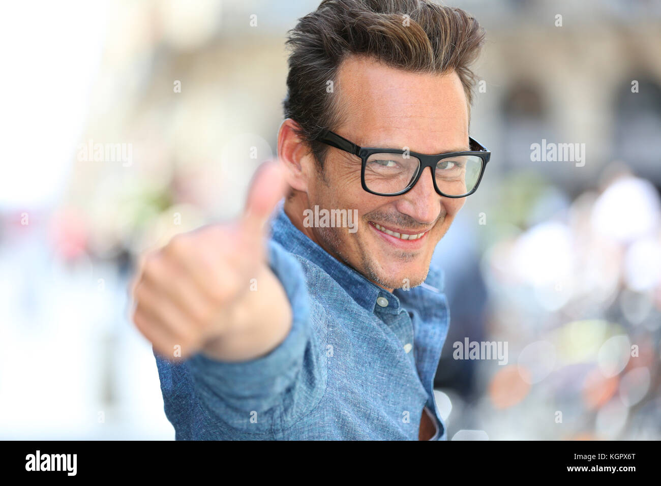 Cheerful guy with eyeglasses showing thumbs up Stock Photo - Alamy