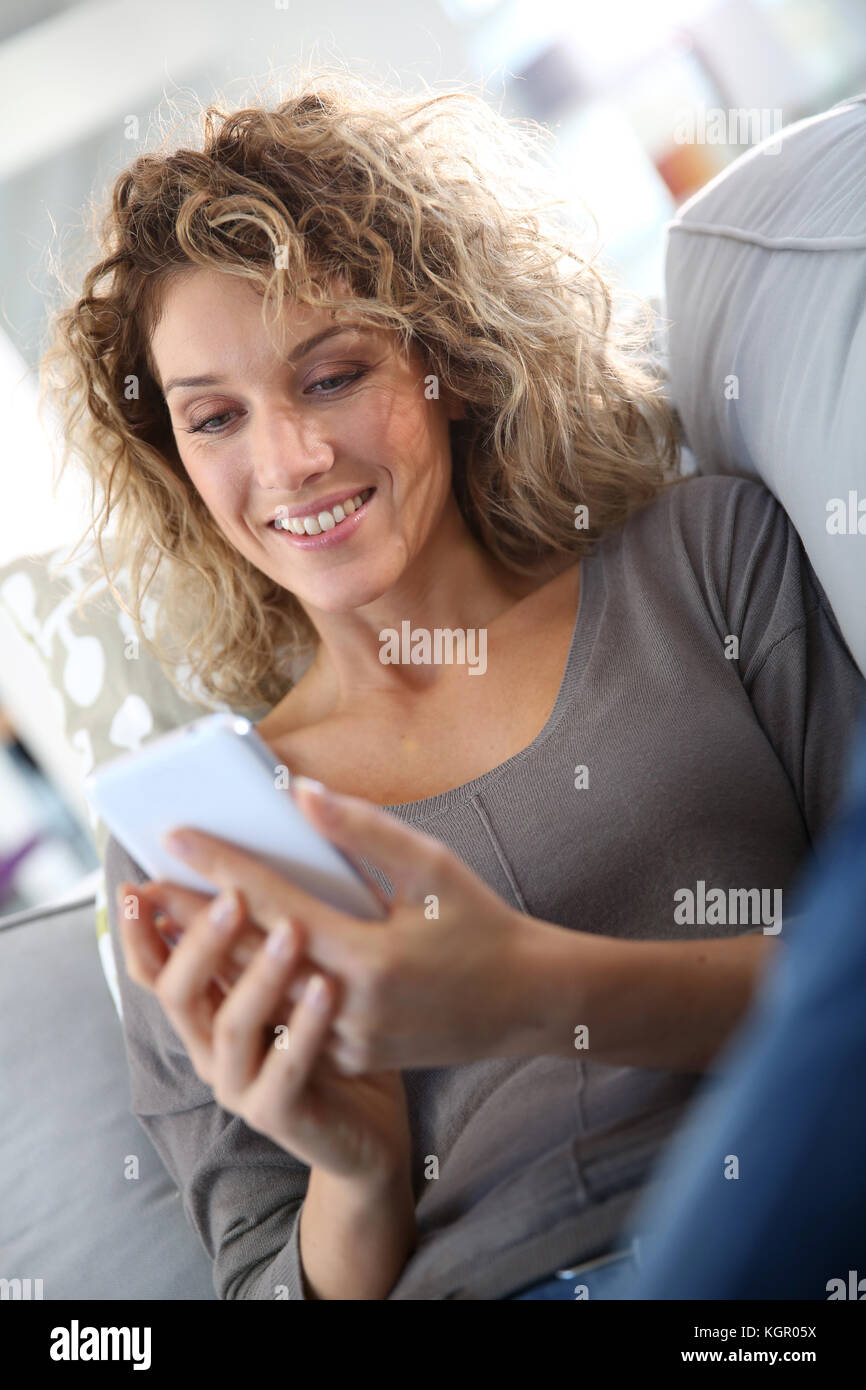 Smiling woman relaxing in sofa with smartphone Stock Photo - Alamy