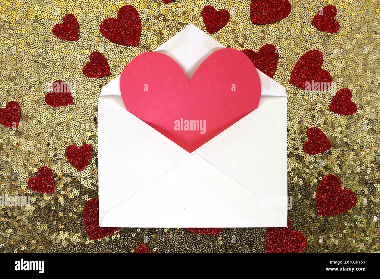 An envelope with a blank red Valentine's day card in it is on a gold ...