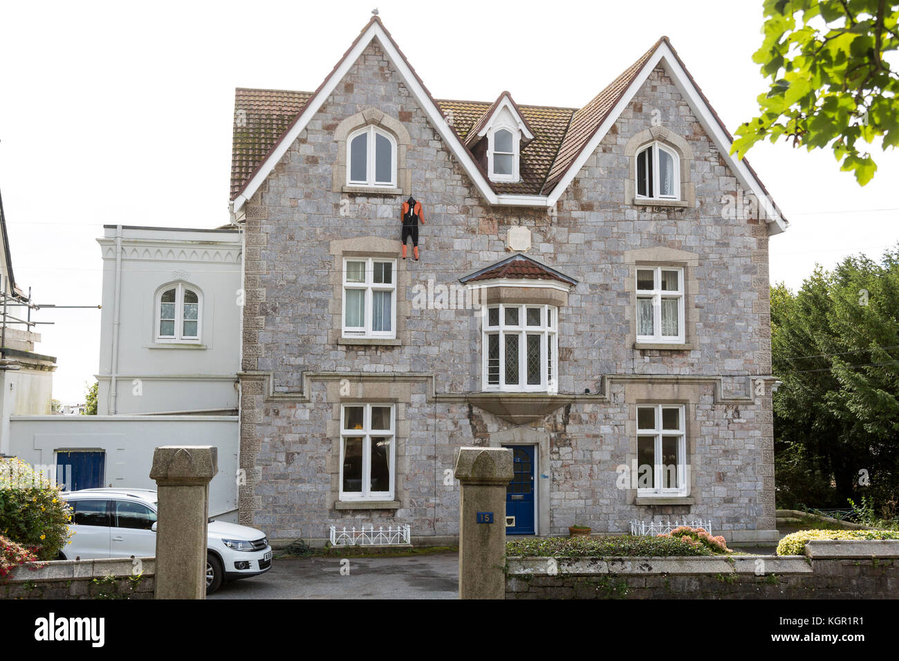 wetsuit hanging out to dry from third floor window of ornate house in Falmouth, UK Stock Photo