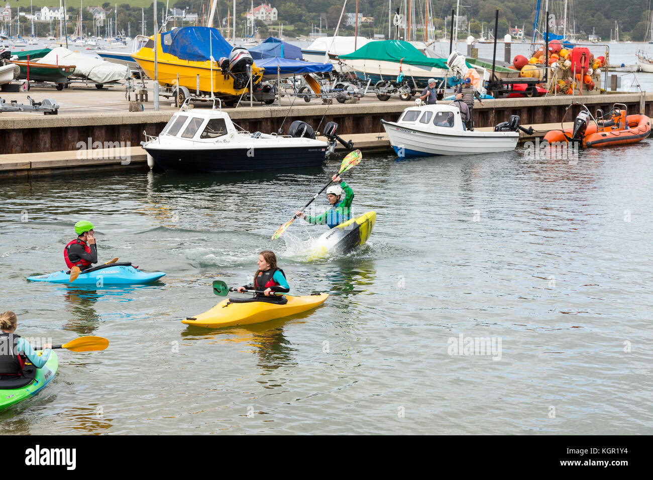 young kayakers training in Falmouth harbour, UK with quayside and boats in background. instructor demonstrating eskimo roll Stock Photo