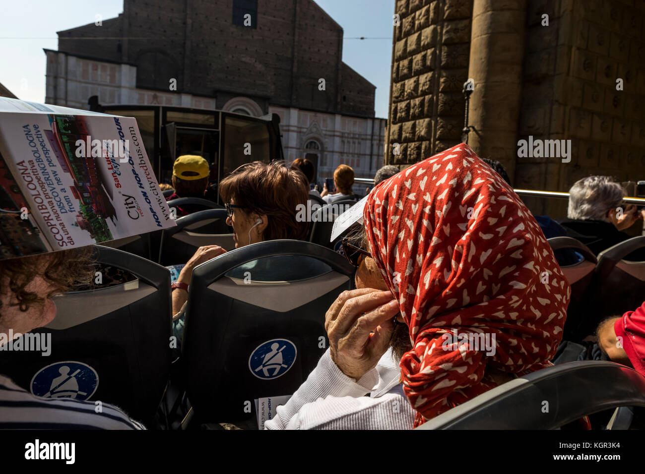 Tourists and visitors take the red bus tour through Piazza Maggiore