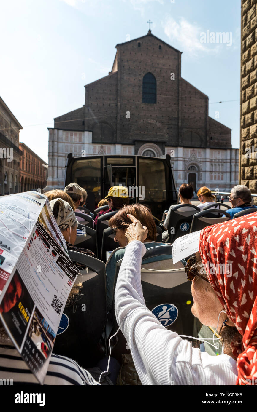 Tourists and visitors take the red bus tour through Piazza Maggiore