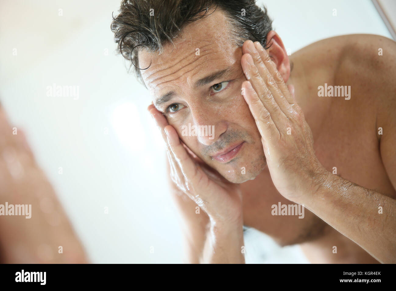 Handsome man rinsing face after shaving Stock Photo