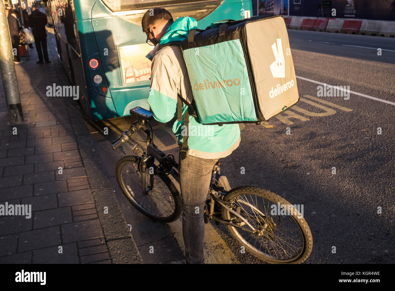 Gig,economy,self employed,Deliveroo,cyclist,bicycle,courier,centre,of,Cardiff,capital,at,sunset,Caerdydd,South Glamorgan,Wales,Welsh,UK,U.K.,Europe, Stock Photo