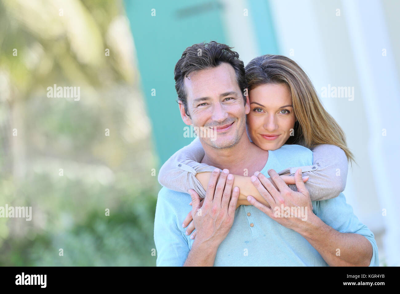 Middle-aged couple embracing in front of house Stock Photo