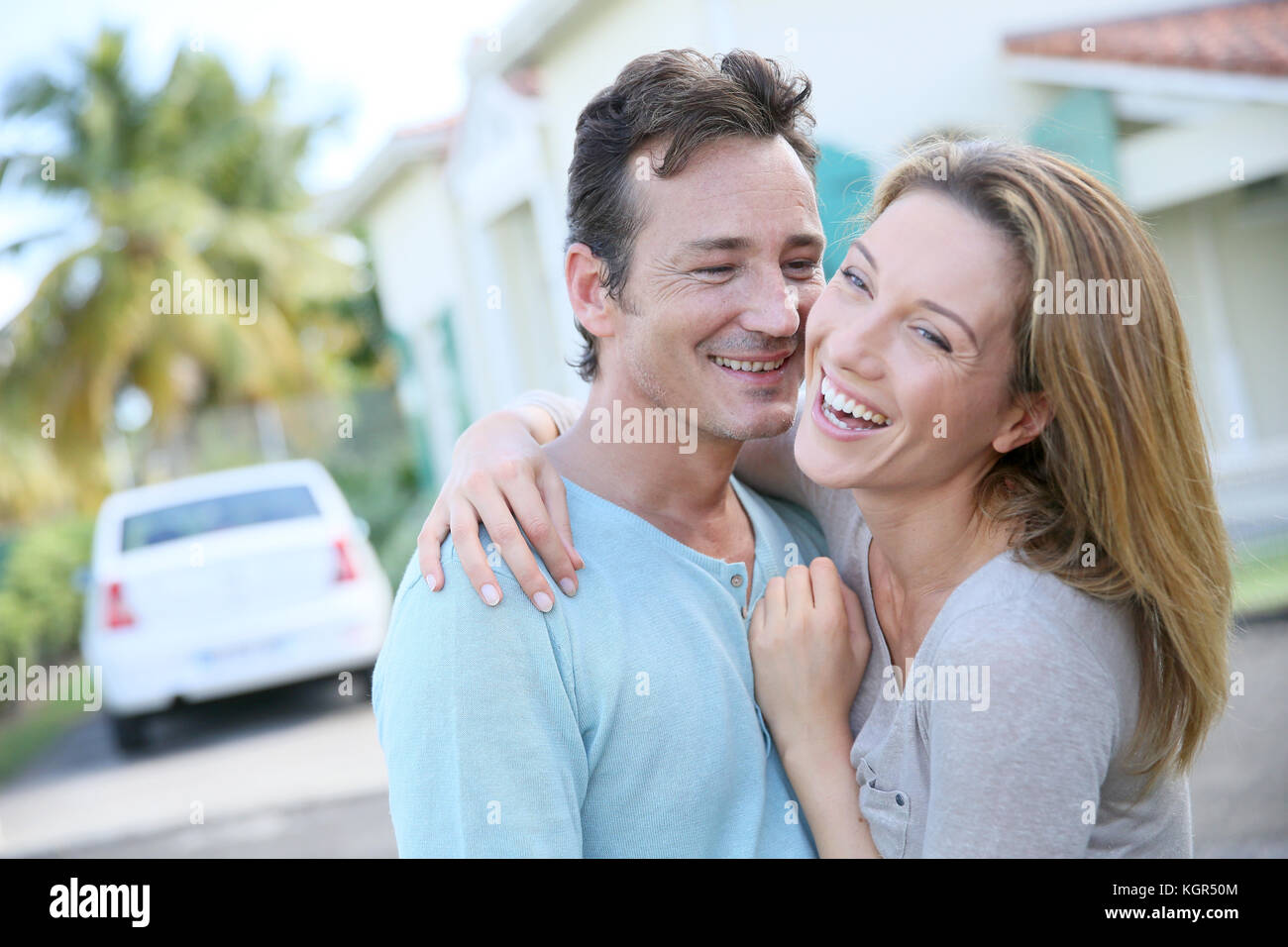Cute loving couple standing in front of home and laughing Stock Photo ...
