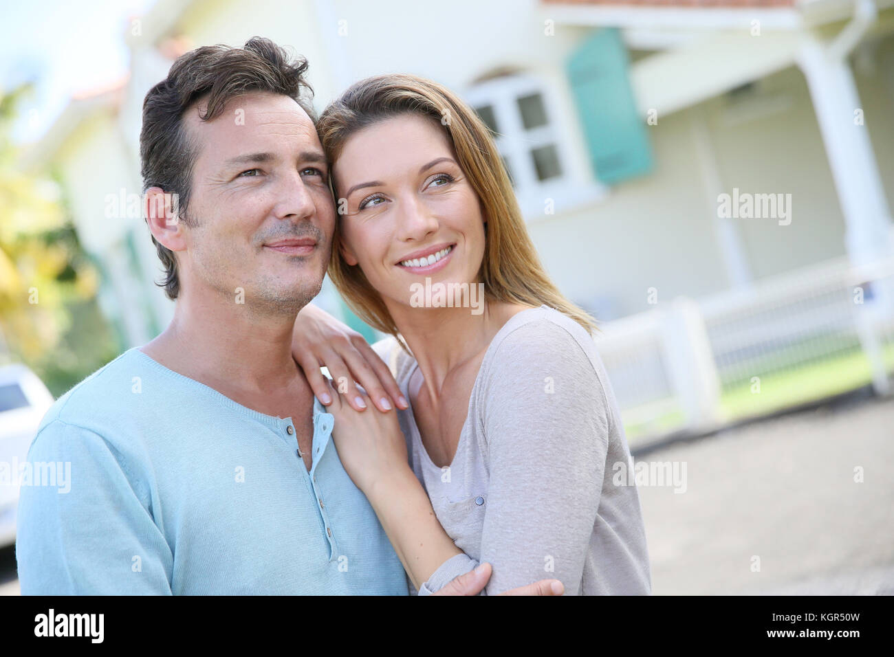Cute loving couple standing in front of home and laughing Stock Photo ...
