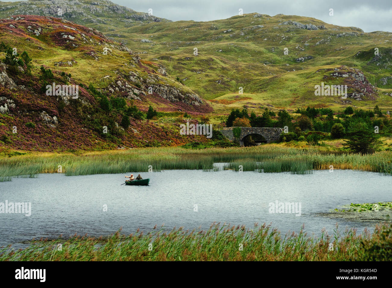 Fly Fisherman fish from a small boat on a lake in the scottish highlands, Scotland Stock Photo