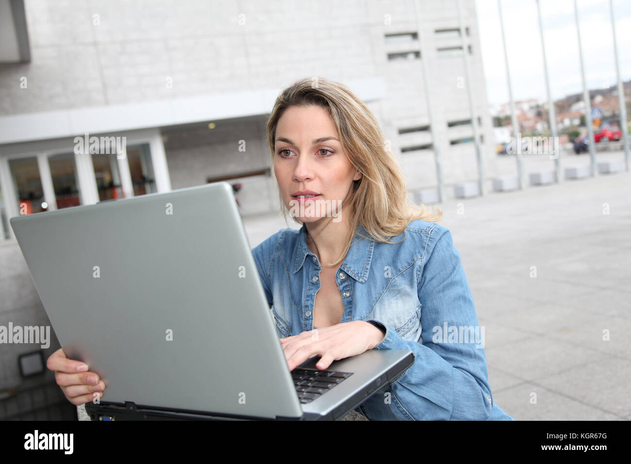 Woman using laptop computer in the street Stock Photo - Alamy