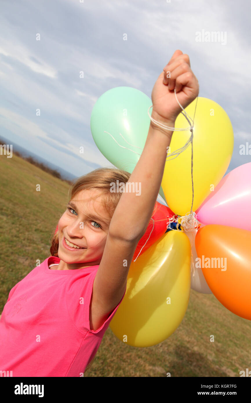 Little girl holding balloons out in the countryside Stock Photo