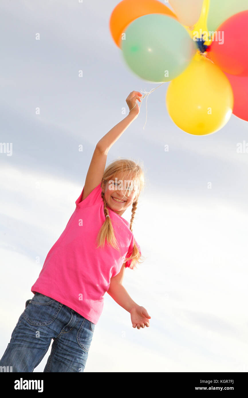 Little girl holding balloons out in the countryside Stock Photo Alamy