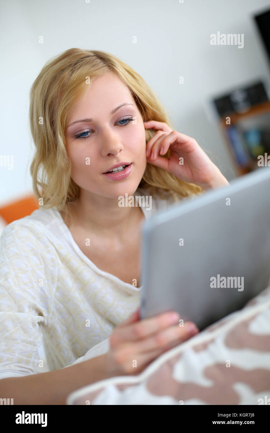 Blond girl sitting in sofa with digital tablet Stock Photo - Alamy